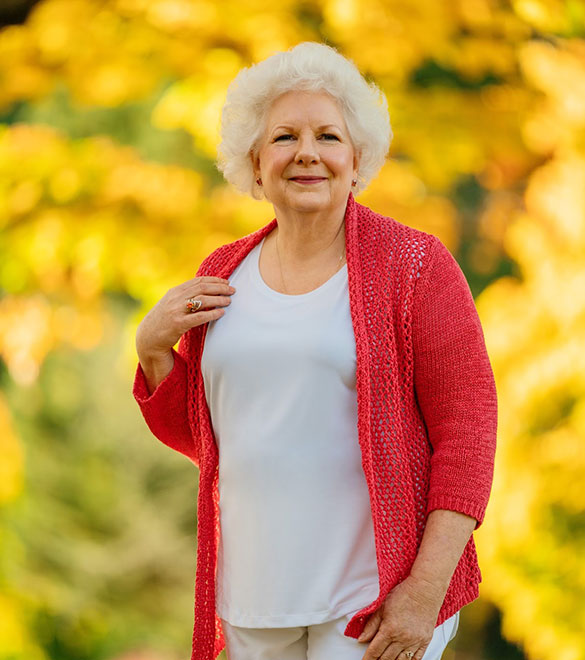 Colleen Bourassa in a bright outdoor setting wearing a red cardigan